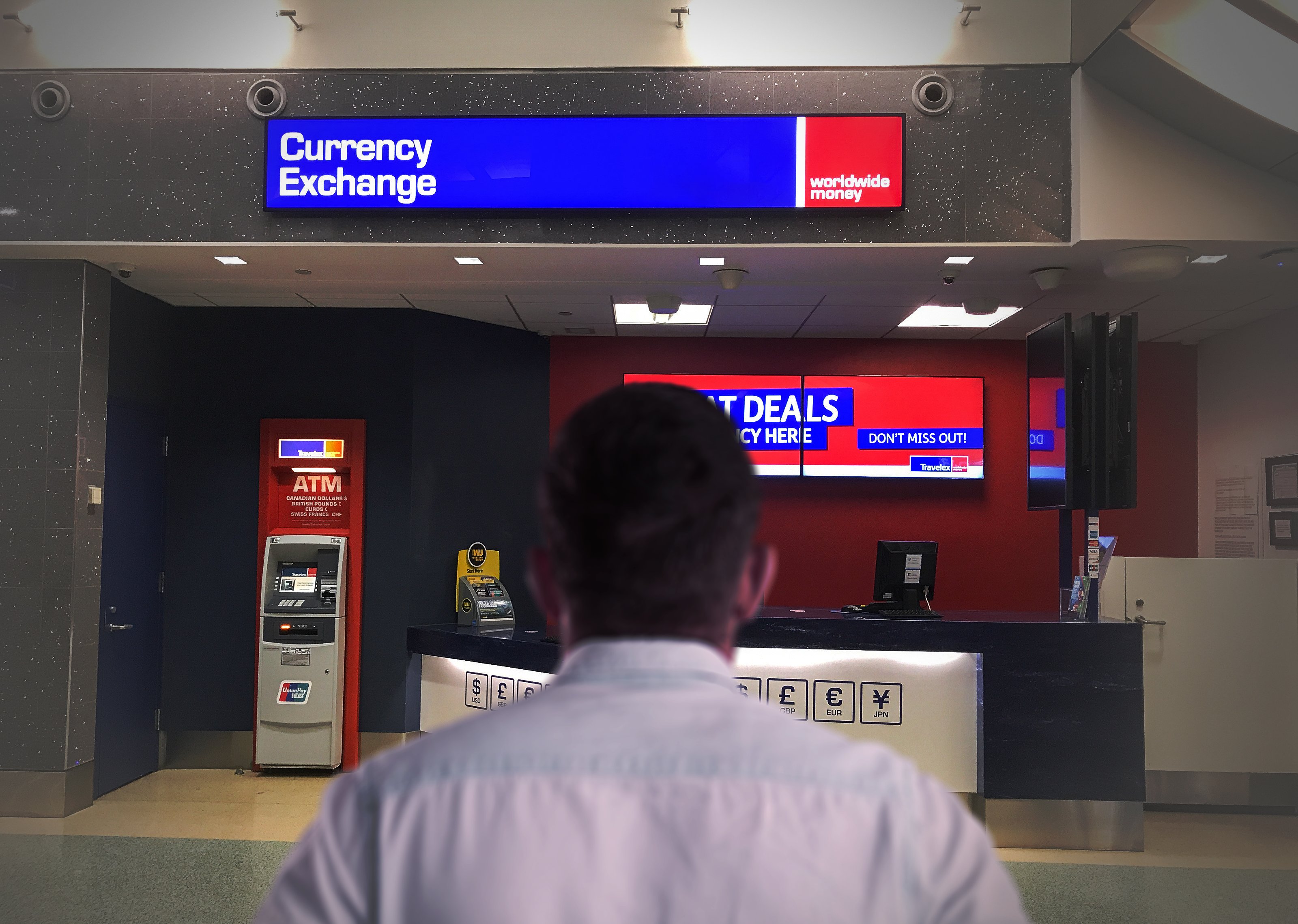 an image of a currency exchange booth at an airport, with travelers exchanging money.